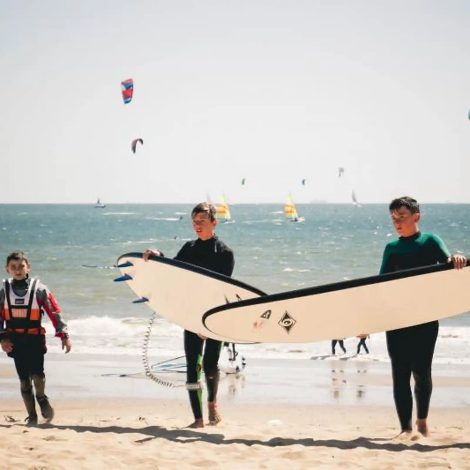 Enfants portant des planches de surf sur la plage de Pornichet