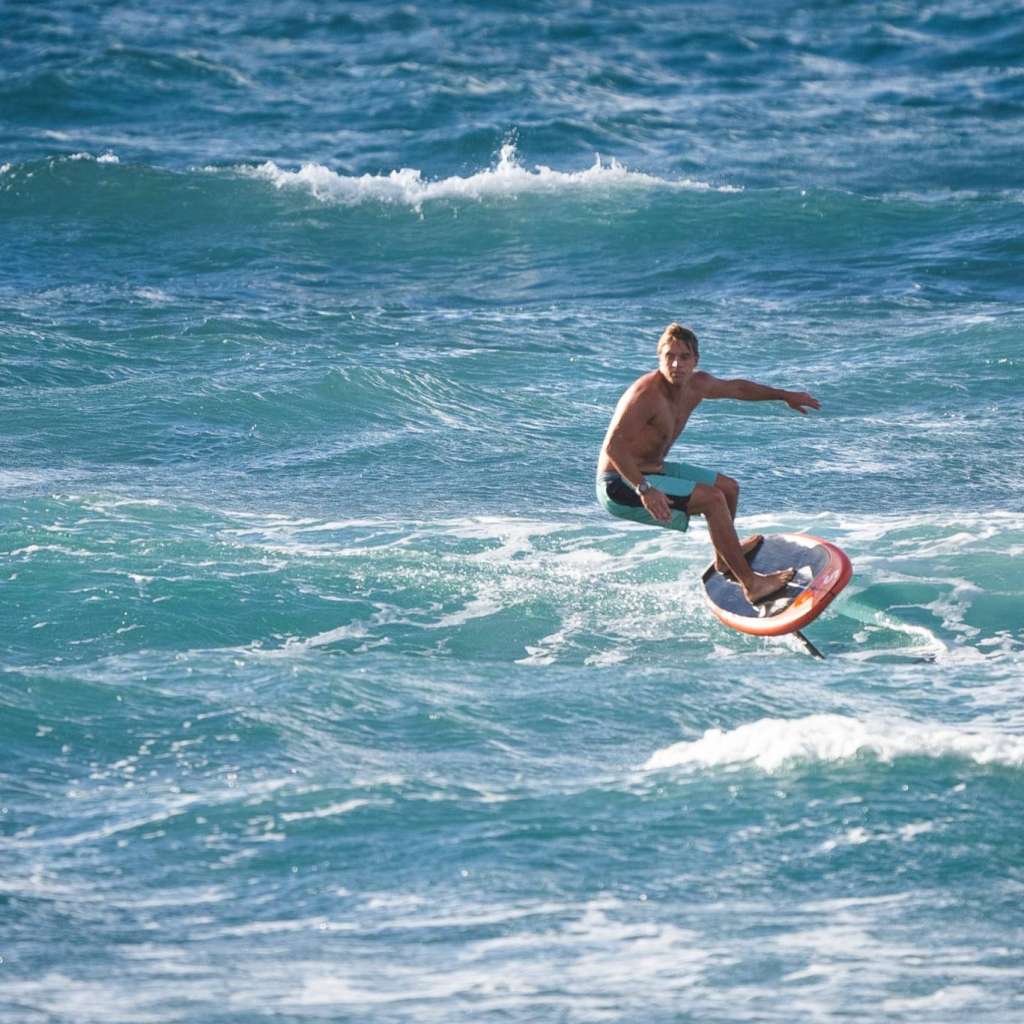 Rider pratiquant le kitesurf en pleine mer sous une météo ensoleillée.