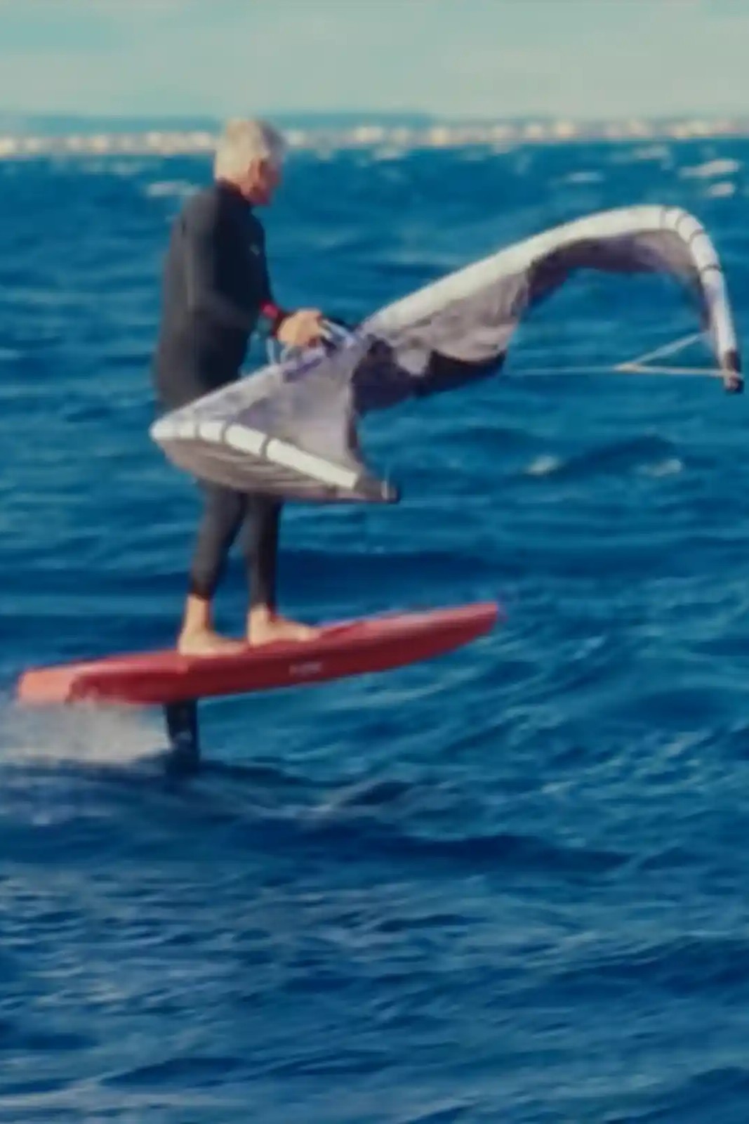 Rider en freefly avec la F-One PLUME 5m² sur foil, aile orange en C-shape stable et légère au-dessus de l’eau.